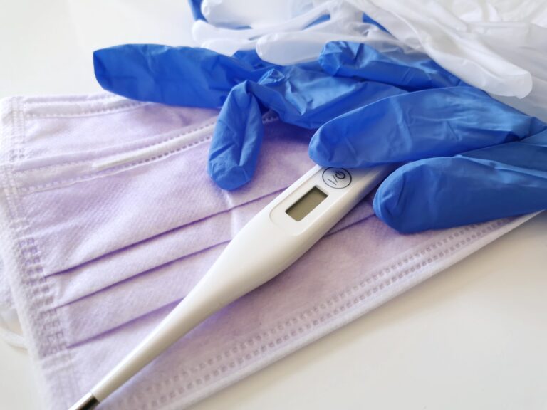 Closeup image of covid epidemic medical supplies. Gloves, masks and thermometer on white background